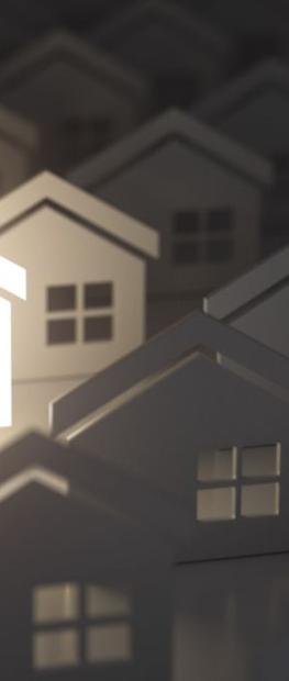 spotlight on a paper cutout house surrounded by other paper cutout houses